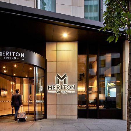 Meriton Suites Sussex Street, Sydney Eksteriør billede The photo shows the entrance of a hotel or suite establishment named "Meriton Suites." The entrance features a revolving door and a large, illuminated sign with the name "MERITON SUITES." The facade is modern and sleek, with a combination of glass an