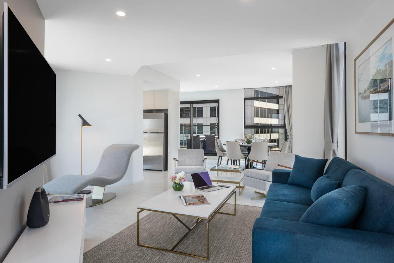 Meriton Suites Sussex Street, Sydney Eksteriør billede The photo shows a modern living space that features a bright and stylish interior. Key elements include:

- A sleek blue sofa and a light gray lounge chair, providing comfortable seating.
- A coffee table with a minimalist design, positioned in front
