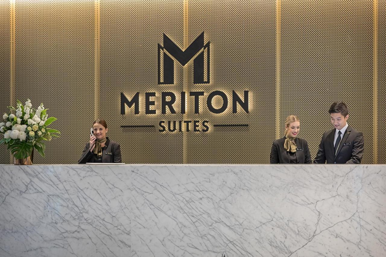 Meriton Suites Sussex Street, Sydney Eksteriør billede The photo depicts the reception area of a hotel called "Meriton Suites." In the background, there is a large, illuminated sign featuring the hotel’s logo. The reception desk is made of marble and is staffed by two individuals dressed in professional 