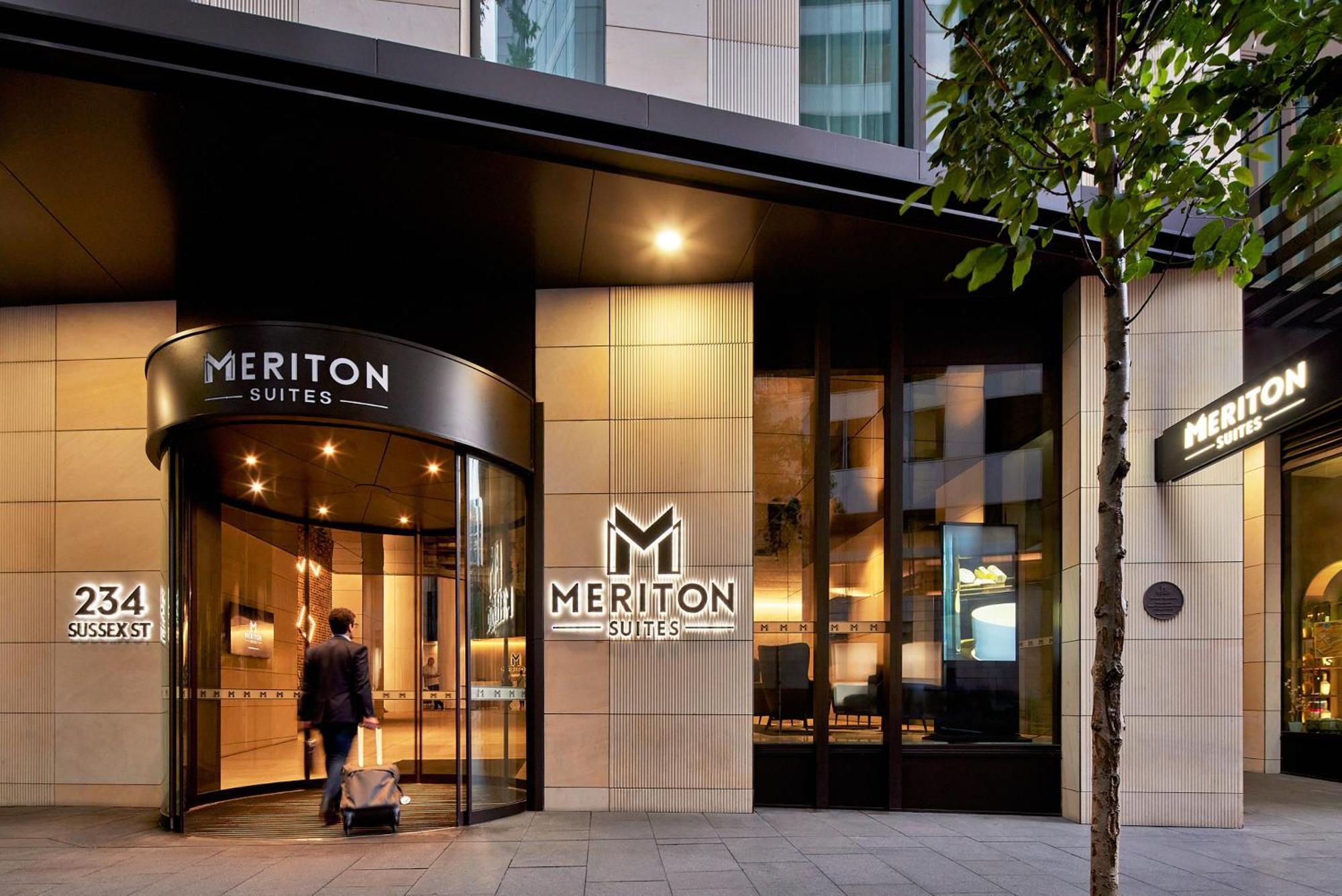 Meriton Suites Sussex Street, Sydney Eksteriør billede The photo shows the entrance of a hotel or suite establishment named "Meriton Suites." The entrance features a revolving door and a large, illuminated sign with the name "MERITON SUITES." The facade is modern and sleek, with a combination of glass an