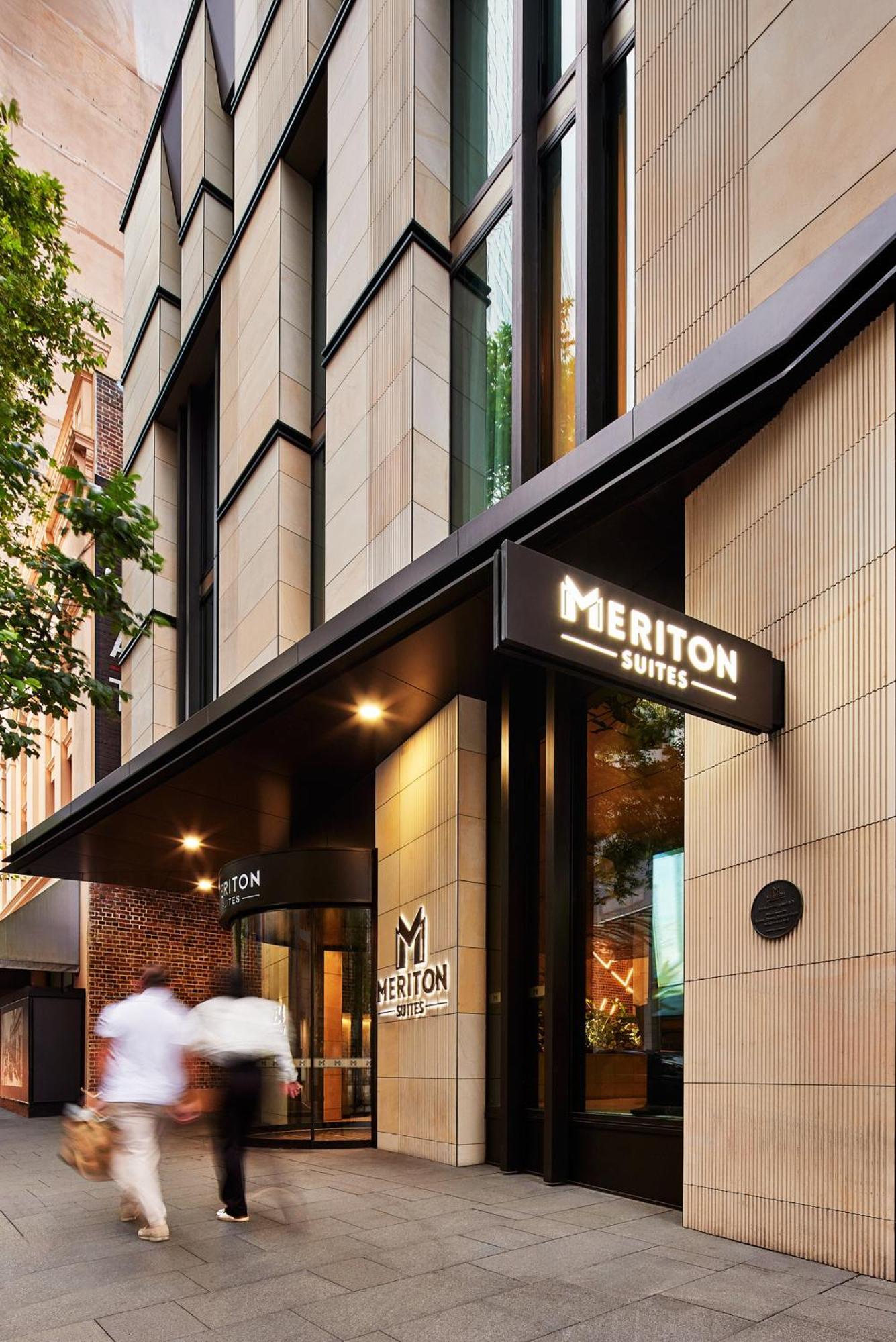 Meriton Suites Sussex Street, Sydney Eksteriør billede The photo shows the exterior of a building with the signage for "Meriton Suites." The entrance features a modern design, with sleek architectural elements and large windows. The entrance is highlighted by a prominent awning and illuminated signs, ind