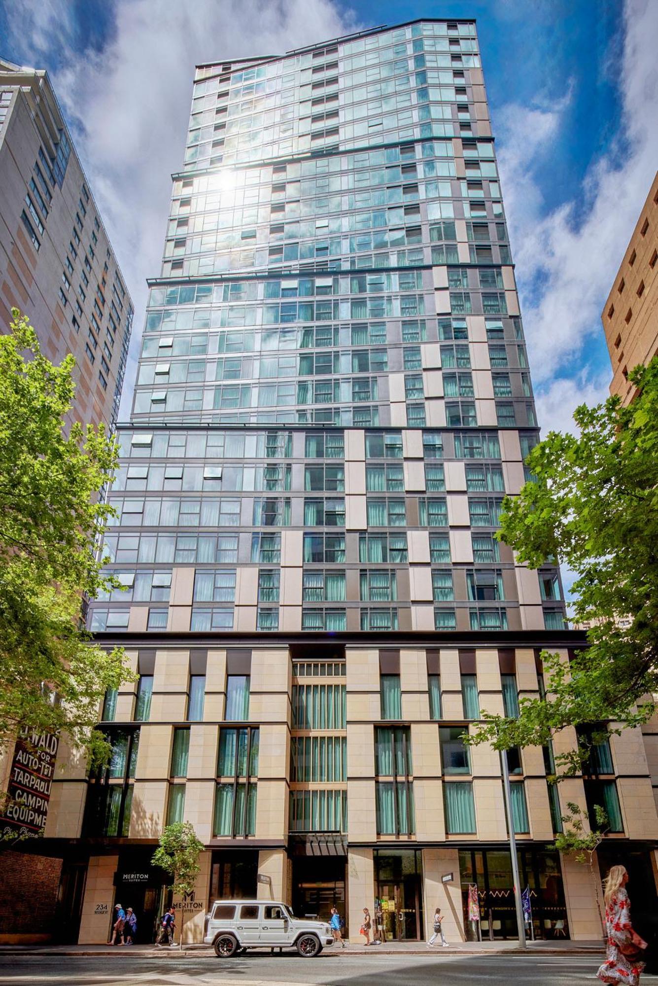 Meriton Suites Sussex Street, Sydney Eksteriør billede The photo shows a tall modern building with a glass facade and various architectural design elements. The structure has multiple stories, with large windows that reflect the surrounding environment. At the base, there are sections that appear to have